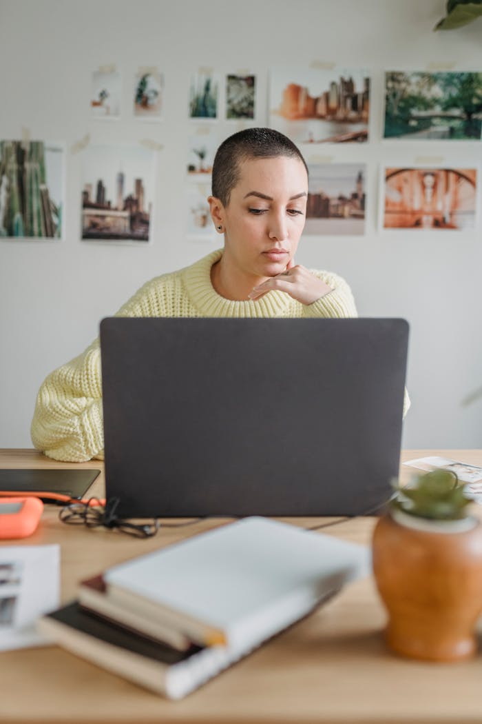 Young woman focused on laptop screen, working remotely in a modern setting.